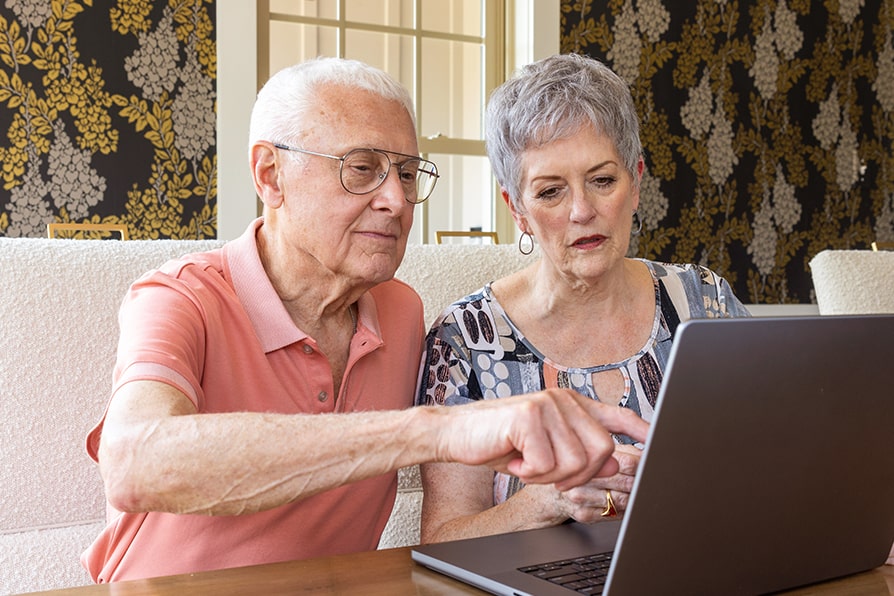 Caregiver ambassador Skip shows Margaret, a YESCARTA® (axicabtagene ciloleucel) patient ambassador, information on the computer.