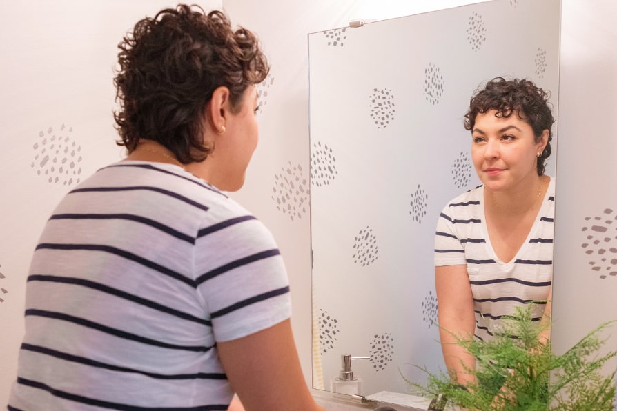 Layra YESCARTA® (axicabtagene ciloleucel) patient ambassador looking in mirror.